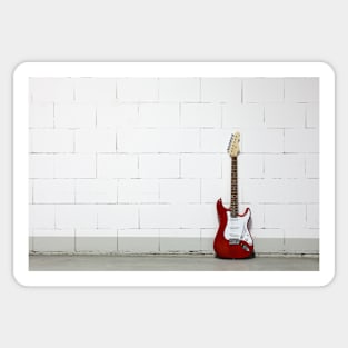 Red electric guitar against white brick wall Sticker